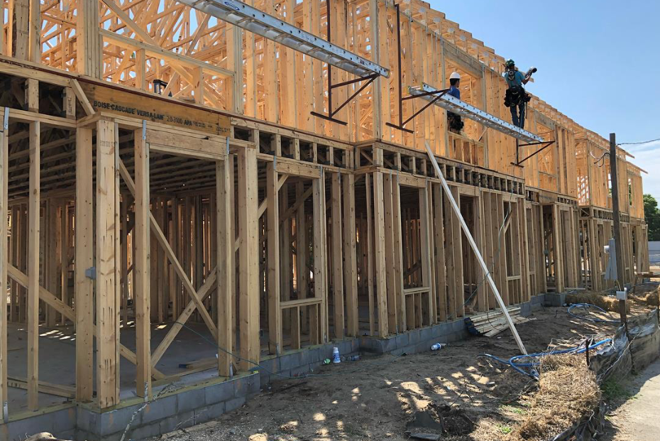 Construction workers building frame of aDoor home.
